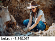 Focused archaeologist carefully excavating relics at a dig site. Стоковое AI-изображение, AI-художник Иван Рябоконь / Фотобанк Лори