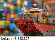 Toy container ship model with colorful intermodal containers on the deck is moored in dry dock. Стоковое AI-изображение, AI-художник Иван Рябоконь / Фотобанк Лори