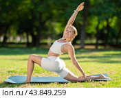 Girl in park on green grass of lawn performs Anjaneyasana. Стоковое фото, фотограф Яков Филимонов / Фотобанк Лори