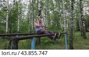 A man does exercises in nature in the summer. A man plays sports on simulators in the forest. Стоковое видео, видеограф Egor Sarantstv / Фотобанк Лори