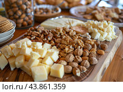 Gourmet cheeseboard displaying variety of cheeses and nuts on wooden table. Стоковое AI-изображение, AI-художник Иван Рябоконь / Фотобанк Лори