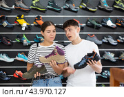 Guy with girlfriend, view specialized shoes in store, near showcase with summer trecking cross-shoes. Стоковое фото, фотограф Яков Филимонов / Фотобанк Лори