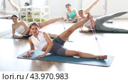 Girls perform exercises lying on side with legs straightened and narrow elastic band on shins. Стоковое видео, видеограф Яков Филимонов / Фотобанк Лори