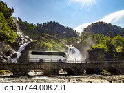 Tourist bus traveling on the road Latefossen Waterfall Odda Norway. Latefoss is a powerful, twin waterfall. Стоковое фото, фотограф Андрей Армягов / Фотобанк Лори