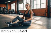 Woman in a bright gym takes a moment to relax after a rigorous training session. Стоковое AI-изображение, AI-художник Tatiana Syrtseva / Фотобанк Лори