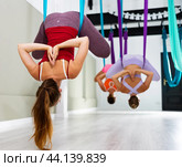 Rear view of woman doing inverted pigeon pose in suspended hammock. Стоковое фото, фотограф Яков Филимонов / Фотобанк Лори