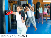 Young hispanic woman in boxing gloves practicing punches on punchbag. Стоковое фото, фотограф Яков Филимонов / Фотобанк Лори