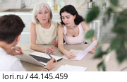 Young male insurance agent offers the best insurance terms for an elderly woman and her adult daughter. Стоковое видео, видеограф Яков Филимонов / Фотобанк Лори