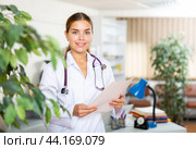 Portrait of a young woman doctor in a office, holding an outpatient patient card in her hands. Стоковое фото, фотограф Яков Филимонов / Фотобанк Лори