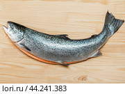 Gutted trout carcass lies on wooden board for cutting fish. Fresh raw salmon red fish on dark wooden background. Sea fish, healthy food. Стоковое фото, фотограф Павел Муравьев / Фотобанк Лори
