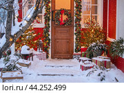 Attractive Christmas entrance decorated with wreath and garlands with snow on the porch. Стоковое фото, фотограф Мария Мороз / Фотобанк Лори