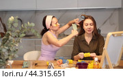 Adult woman curls hair of young woman. Стоковое видео, видеограф Яков Филимонов / Фотобанк Лори