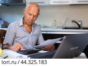 Senior man calculates profits and losses of online trading on calculator. Стоковое фото, фотограф Татьяна Яцевич / Фотобанк Лори