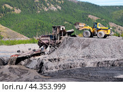 Фронтальный колесный погрузчик Komatsu WA 500 высыпает на промывку горный золотосодержащий грунт, в бункер промывочной машины. Республика САХА, ЯКУТИЯ, Оймяконский район. (2009 год). Редакционное фото, фотограф Павел Просянов / Фотобанк Лори