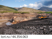 Японский Бульдозер Komatsu D375 в горной местности, боронит верхний слой горного грунта, чтобы затем его сгрести ковшом в отвал. На дальнем плане - стационарное промывочное устройство для промывки золота (2009 год). Редакционное фото, фотограф Павел Просянов / Фотобанк Лори