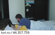 A man is lying in bed working on a laptop. Стоковое видео, видеограф Ярославский Максим / Фотобанк Лори