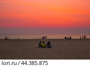 Group of people, family sitting on sand, having a picnic at sunset by the sea. Thailand, Pattaya (2024 год). Редакционное фото, фотограф Коханова Наталья / Фотобанк Лори