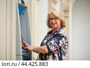Mature blonde woman counting money near ATM. Стоковое фото, фотограф Андрей Аркуша / Фотобанк Лори