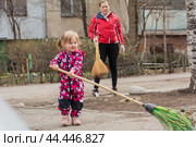 A two-year-old girl helps her parents to harvest the leaves in the spring. Стоковое фото, фотограф Evgenii Predibailo / Фотобанк Лори