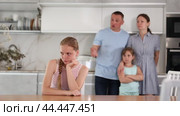 Frowning aggrieved teenage girl sitting at table in home kitchen, listening to reprimand of father standing in background. Concept of family conflicts and misunderstanding of children. Стоковое видео, видеограф Яков Филимонов / Фотобанк Лори