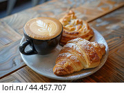 Delicious croissant and latte on wooden table. Стоковое AI-изображение, AI-художник Иван Рябоконь / Фотобанк Лори