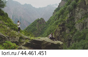 Group of tourists, while hiking in the mountains, decided to arrange a photo shoot on a large rock. Slow motion. Стоковое видео, видеограф Strunov David / Фотобанк Лори