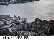 Aerial view of Bergen harbor in Norway with a docked cruise ship surrounded by modern and traditional buildings (2019 год). Редакционное фото, фотограф KOSIM / Фотобанк Лори