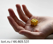 Open hand holding yellow dice for chance and luck concepts. Стоковое фото, фотограф Lamina Akulova / Фотобанк Лори