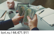 Counting cash while managing personal finances at a desk with a calculator and a piggy bank. Стоковое видео, видеограф Сергей Толмачёв / Фотобанк Лори