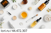 Selection of skincare products arranged artfully on a white background with various bottles, jars, and applicators around natural elements. Стоковое AI-изображение, AI-художник Сергей Толмачёв / Фотобанк Лори