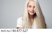 Portrait of a smiling cheerful blonde teenage girl with long white hair and perfect skin, white background, banner. Стоковое AI-изображение, AI-художник ALLA YURTAYEVA / Фотобанк Лори