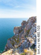 Lake Baikal on sunny autumn day. Typical view of lake with steep cliffs covered with red lichens and mosses and endless expanse of blue water to horizon. Travels on Tazheran steppe, coast of Baikal lake. Стоковое фото, фотограф Виктория Катьянова / Фотобанк Лори