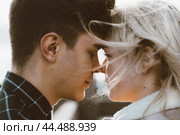 The boy looks tenderly at girl and wants to kiss. A young couple stands embracing. The concept of teenage love and first kiss, sincere feelings of man and woman. The city, the waterfront. Close up. Стоковое фото, фотограф Natalia Gdovskaia / Фотобанк Лори