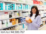 Latin american woman looking for haircare products at cosmetics shop. Стоковое фото, фотограф Яков Филимонов / Фотобанк Лори