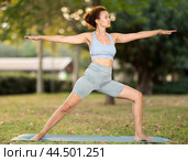 Woman practicing yoga in garden, performing Anjaneyasana, or Crescent Moon Pose. Стоковое фото, фотограф Яков Филимонов / Фотобанк Лори