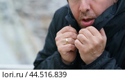 Middle aged handsome man in cold day outdoors. Too cold. Concept of leisure time, cold weather during winter season. He's trying to wrap himself up. Portrait, front view. Close up. Walking without hat. Стоковое фото, фотограф YuryKara / Фотобанк Лори