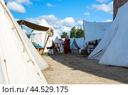 Девушка прогуливается между палатками в средневековом лагере. Фрагмент исторического фестиваля "Дни средневековья в Выборге-2024" Редакционное фото, фотограф Дмитрий Мельников / Фотобанк Лори