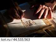 Мужчина пишет вязью, древним декоративным кириллическим письмом, на листе бумаги в городе Москве, Россия. Редакционное фото, фотограф Николай Винокуров / Фотобанк Лори