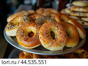 Freshly baked assorted bagels display. Стоковое AI-изображение, AI-художник Иван Рябоконь / Фотобанк Лори