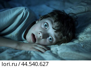 Frightened child in bed at night. Стоковое AI-изображение, AI-художник Иван Рябоконь / Фотобанк Лори