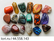 Vibrant array of various polished semiprecious stones on a white background. Стоковое AI-изображение, AI-художник Иван Рябоконь / Фотобанк Лори