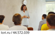 Positive male tutor giving lecture as part of educational program while standing in front of group of men in study hall. Стоковое видео, видеограф Яков Филимонов / Фотобанк Лори