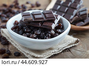Dark chocolate bar pieces and raisins in bowl. Стоковое AI-изображение, AI-художник Иван Рябоконь / Фотобанк Лори