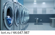 Modern laundromat with high-efficiency washers operating in a clean, well-lit environment during the daytime. Стоковое AI-изображение, AI-художник Сергей Толмачёв / Фотобанк Лори