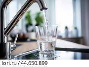 Filling a glass cup from a kitchen faucet. Стоковое AI-изображение, AI-художник Veniamin Kraskov / Фотобанк Лори