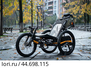 Modern three wheeled recumbent bicycle standing on a cobblestone path. Стоковое AI-изображение, AI-художник Иван Рябоконь / Фотобанк Лори