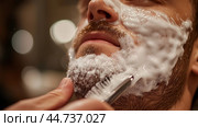 A man enjoys a relaxing shave with rich lather in a barbershop during late evening hours surrounded by warm, ambient lighting. Стоковое AI-изображение, AI-художник Сергей Толмачёв / Фотобанк Лори