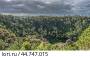 Thickets of lush green vegetation surround the crater of an extinct volcano. The lake is visible at the bottom. Clouds in the sky. Mauritius. Trou-aux-Cerfs (2024 год). Стоковое фото, фотограф Вера Ивановна Кубарева / Фотобанк Лори