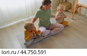 Mindful meditation activities mother with kids in a cozy indoor space. Relaxation and connection. Engaging in a relaxing meditation session mom with children. Warm and inviting atmosphere at home. Стоковое видео, видеограф Марина Демидюк / Фотобанк Лори