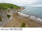 Charming Zumaia Itzurun beach. Steeply-tilted layers of flysch. Atlantic ocean surf and lonely house in Basque Autonomous Community  in day in Bay of Biscay. View from above / top view. Стоковое фото, фотограф YuryKara / Фотобанк Лори